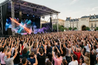 Concert international en plein air à Lyon avec une foule enthousiaste et un artiste sur scène devant un écran LED